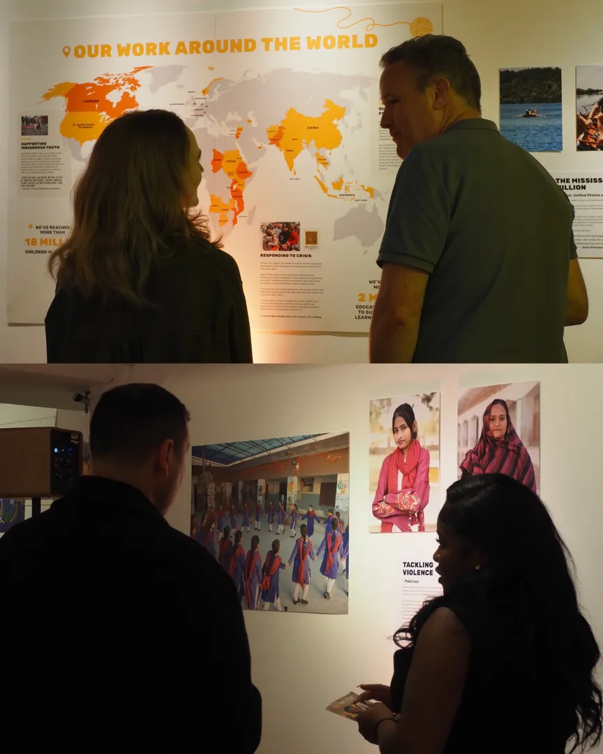 Visitors look at the display, including photos of children and a map of where Right To Play works