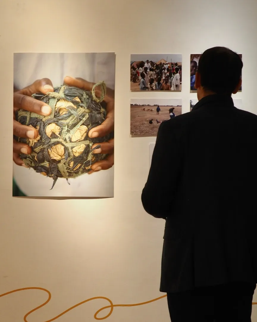 A guest stands in front of a wall at the exhibition which displays a large photograph of a ball made of tied fabric