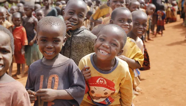 A group of children stand in line in a sandy field smiling at the camera